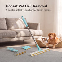 The Meoggy All-Surface Tool leaning against a rug in a living room, with a cat and dog resting together on a bed nearby
